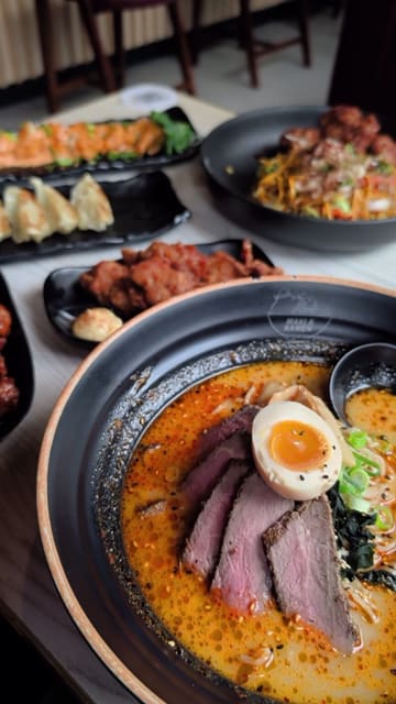 A montage video showcasing the interior, food, and drinks at a Maki & Ramen restaurant. The video features shots of ramen, small plates, cocktails, and mochi, alongside the restaurant's signature cherry blossom decor and a wall covered in customer notes.