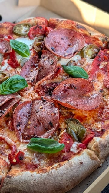 A short, music-led montage showcasing wood-fired pizzas being prepared and served at Hummingbird Cafe. The video focuses on the cooking process, the final product, and the menu, emphasizing the quality of the sourdough base and toppings.