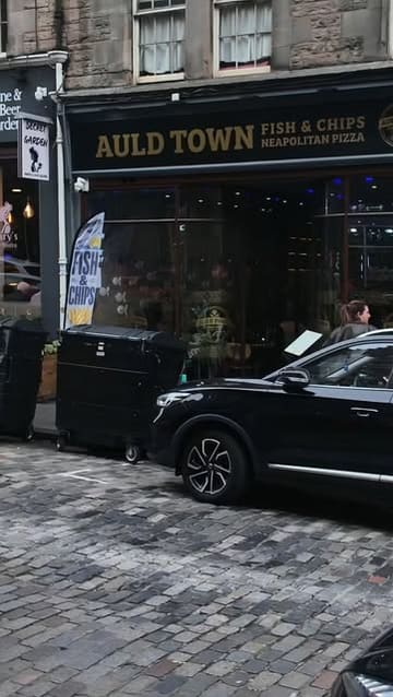 A review-style video featuring two creators visiting Auld Town Fish & Chips in Edinburgh. The video includes shots of the exterior, interior, and several dishes including haggis bonbons, fish and chips, a burger, and a steak pie.
