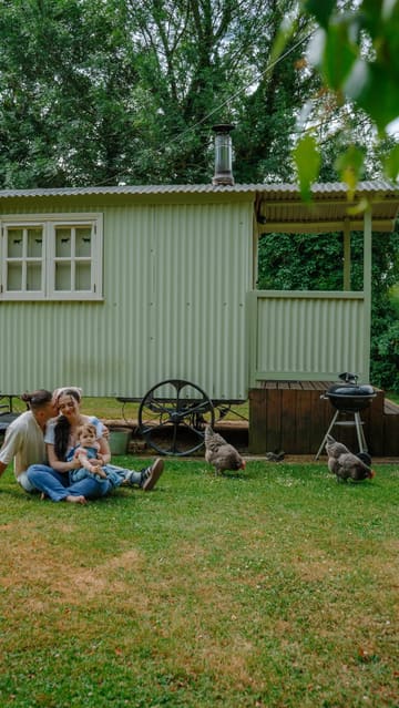 A family vlog showcasing a stay at a shepherd's hut lodge, highlighting the peaceful nature setting, breakfast cooking, and interactions with resident chickens.