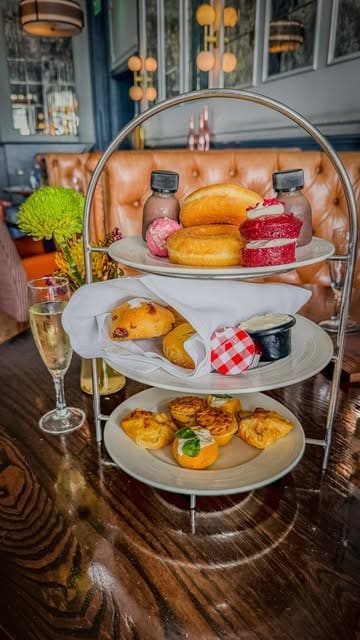 A montage showcasing an afternoon tea experience at the Hilton Metropole, featuring both adult and children's menus, with shots of the venue, sea views, and the food spread.