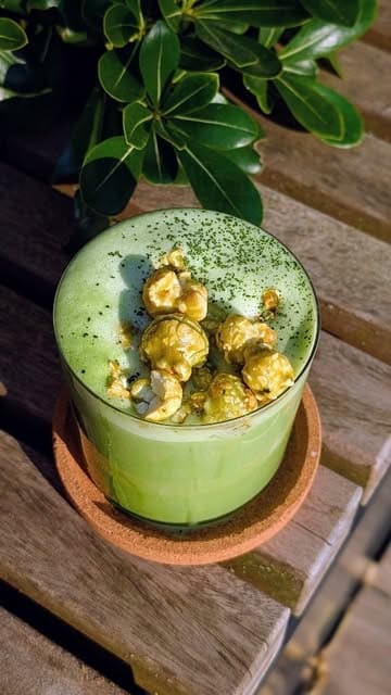 A short, visually appealing recipe video demonstrating how to make a Matcha Caramel Popcorn Latte at home using oat milk and caramel-flavored barista milk.