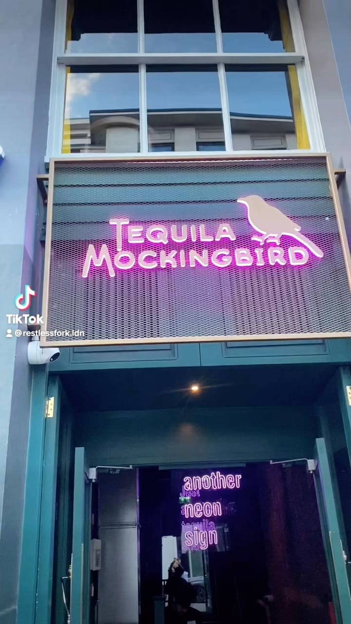 The video showcases Tequila Mockingbird, a bar in London. It features various cocktails, including those in tiki mugs and martini glasses. The cocktails are presented with creative garnishes like cotton candy. The video highlights the bar's neon signs and ambiance. The main focus is showcasing the cocktails and the bar's atmosphere.