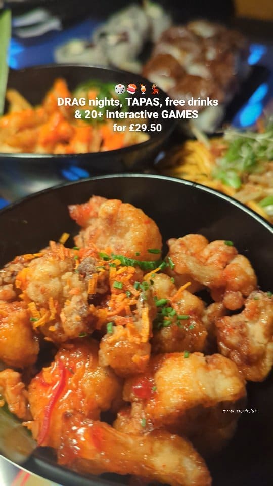 The video promotes Inamo restaurant in Covent Garden, London. It showcases various tapas dishes including sushi, bao buns with fried chicken, cauliflower in a sauce, and other small plates. The restaurant's interactive tables are highlighted, and a drag queen performing is featured. The video emphasizes the deal of tapas, free drinks, and games for £29.50.  The food presentation is mostly close-up shots, some showing the full table setting.