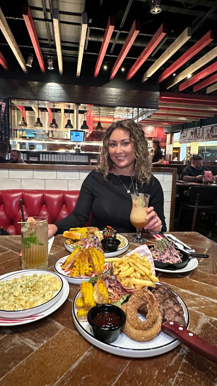 The video showcases a dining experience at a TGI Fridays restaurant. It features a variety of dishes including a New York strip steak with fries and onion rings, blackened salmon with mashed potatoes, mac & cheese, corn ribs, and coleslaw. Drinks shown are two cocktails/mocktails. Desserts featured are Key Lime Pie and Pecan Pie. The video also highlights the American diner-style interior and ambiance of the restaurant. The overall focus is on the new menu items and the enjoyable, fun atmosphere.