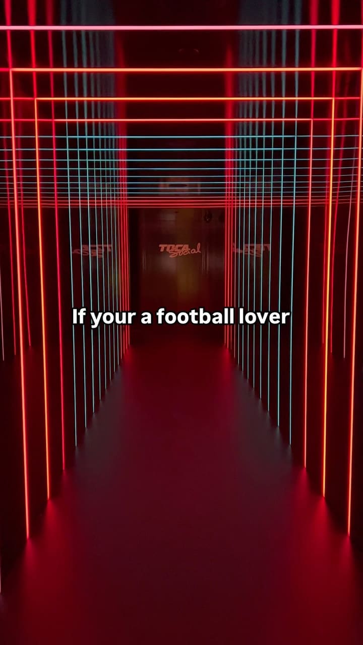 The video showcases TOCA Social, an interactive football and dining experience at the O2 in London.  It features two boys and their father playing interactive football games using projected technology. The venue's interior, which includes a bar area with tables and chairs, is also shown.  No specific food or drinks are prominently displayed.