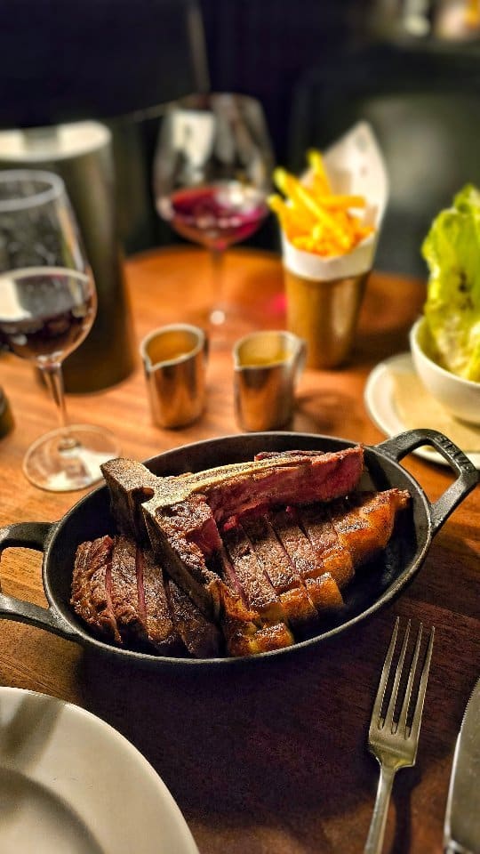The video showcases a meal at the Hawksmoor Knightsbridge steakhouse.  It features various dishes: oysters on ice, a whole roasted lobster with lemon and herbs, and a porterhouse steak sliced and served in a cast iron dish.  The presentation is elegant and focuses on high-quality ingredients. There is no mention of dietary information. The main focus is on showcasing the food and dining experience at the restaurant.