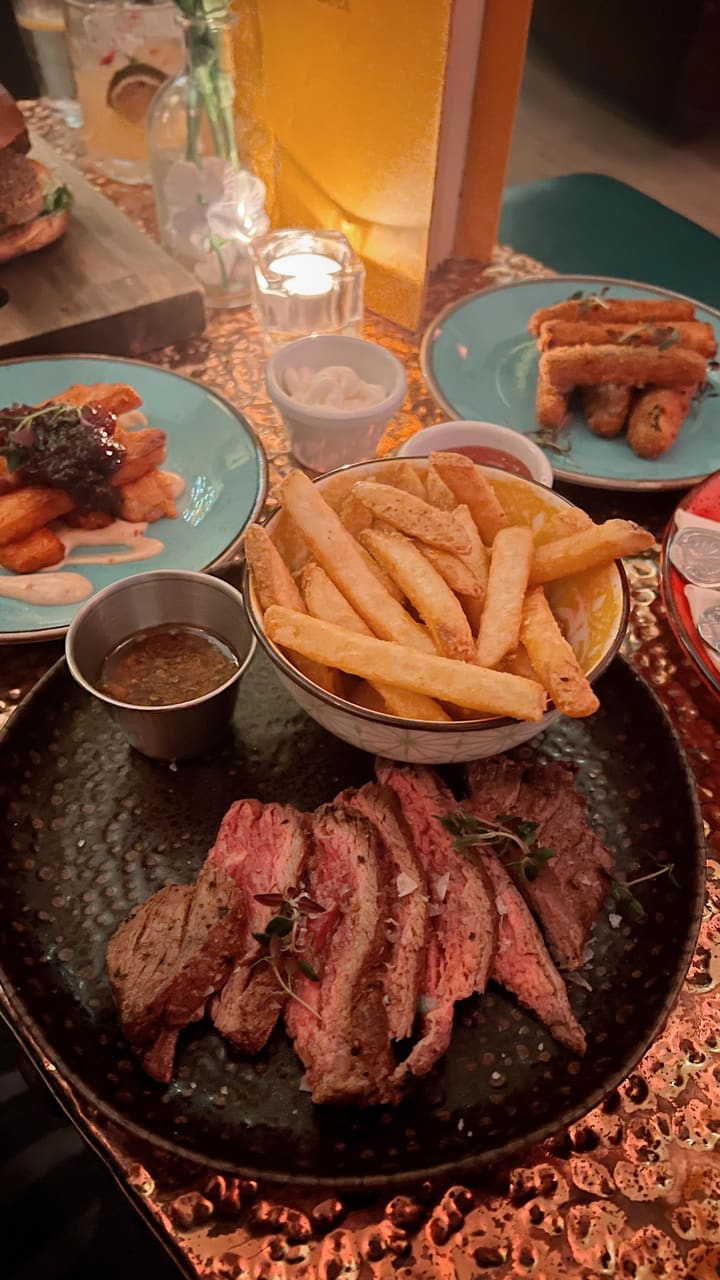 The video showcases The Little Blue Door, a bar in Fulham Road, London. It highlights their cocktails (Tommy's Margarita and Picante), food (vegetarian burger with fries, various small plates, and a steak and chips special), and the bar's interior design.  The presentation is vibrant, showcasing a mix of colorful decorations and the food in various angles.  The video doesn't explicitly mention any dietary restrictions but shows vegetarian options. The main focus is on the overall dining and drinking experience at the establishment.