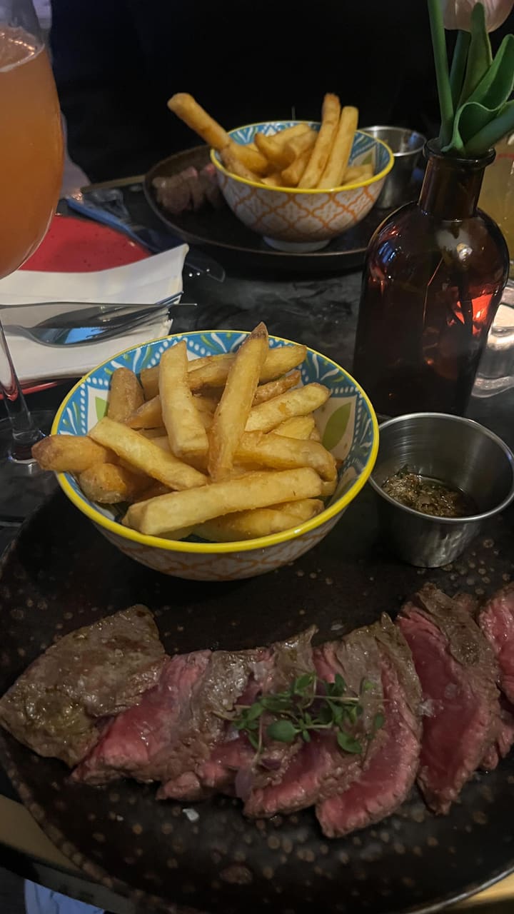 This video showcases a visit to The Little Blue Door Fulham restaurant. It features various dishes, including halloumi fries with a berry sauce, sea bass tacos with guacamole and a creamy sauce, and steak with chips.  The cocktails shown are a margarita-style drink and a larger cocktail garnished with a toasted marshmallow. The video emphasizes the food and drink, the restaurant's ambiance, and the overall experience.