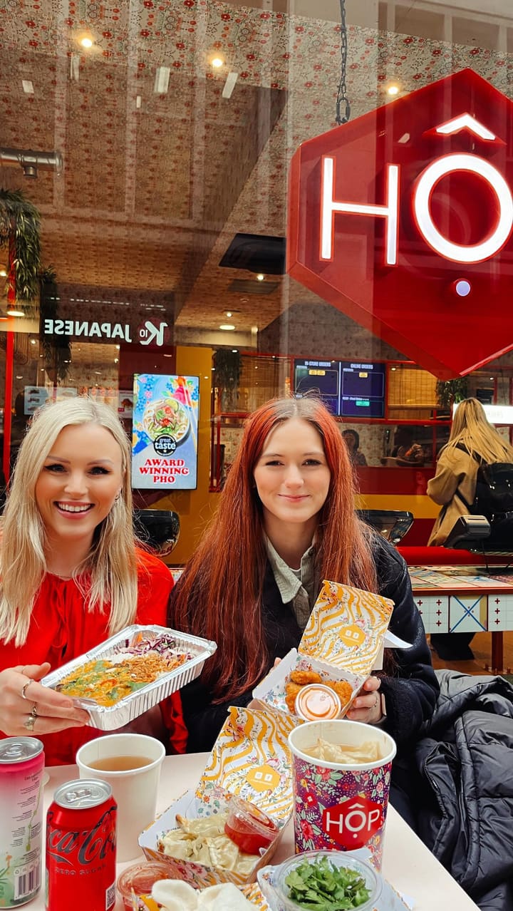 This video showcases a visit to Hop Vietnamese Kitchen in London. Two young women order and enjoy several vegan dishes, including a coconut curry hop box with Fable mushroom, dumplings, prawn crackers, and popcorn chick'n. The video highlights the food's presentation and emphasizes the flavorful and affordable options. The setting is primarily the restaurant and an outdoor seating area.