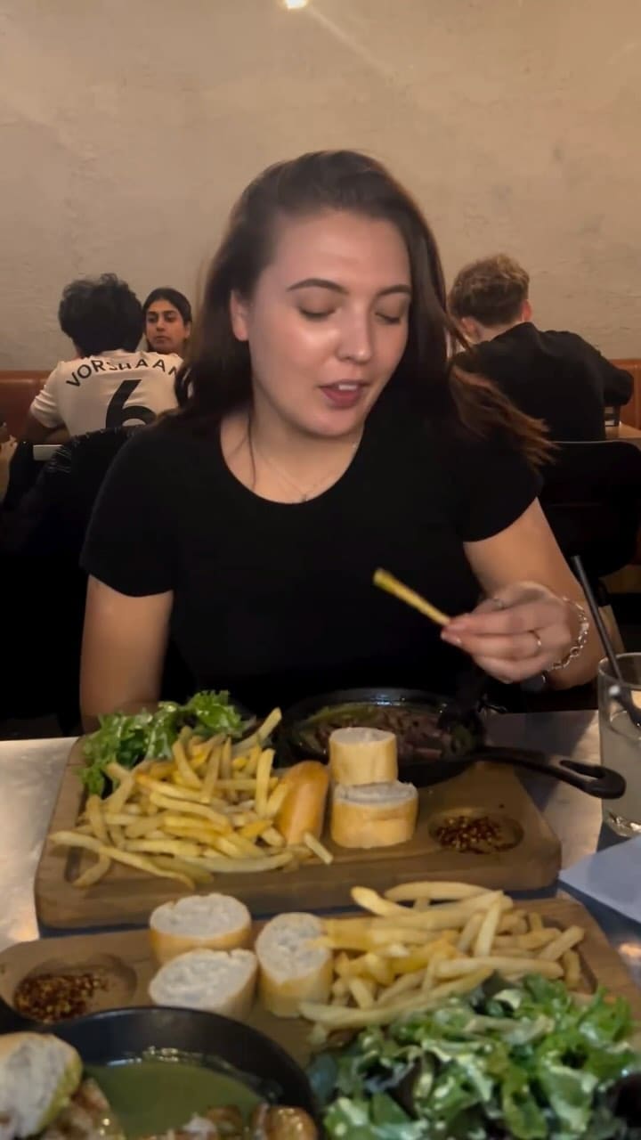 The video showcases a meal from Swiss Butter in Holborn, London. It features grilled sliced steak in a green sauce, served with french fries, a side salad with yellow dressing, and slices of baguette.  Two desserts are also presented: a molten chocolate cake and a pain perdu. The main focus is on the food presentation and the influencer's positive experience.