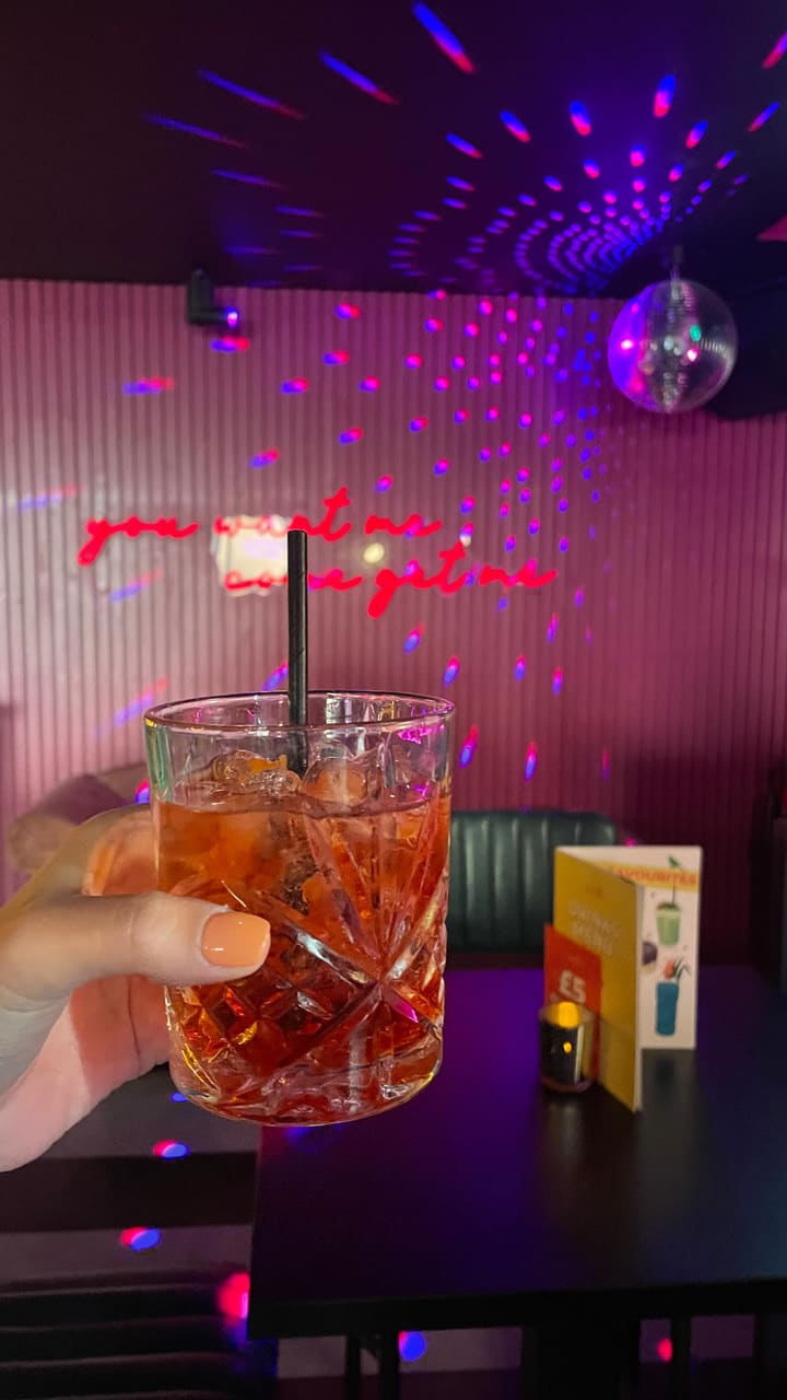 The video showcases the preparation and enjoyment of Negroni Sbagliato cocktails in a vibrant, dimly lit bar setting.  The cocktails are presented in short rocks glasses with ice and an orange peel garnish. The bartender expertly mixes the drinks, emphasizing the inclusion of Prosecco. The video focuses on the preparation and the celebratory atmosphere surrounding the cocktails, with minimal emphasis on any food items.  No specific dietary information is mentioned.
