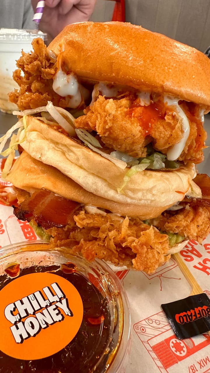 The video showcases a visit to Butchies, a fried chicken restaurant in Ealing, London. The content focuses on two chicken burgers (the Buffalo and the Jenny from the Block), hot shake fries, and milkshakes.  The food is presented in detail, emphasizing textures and colors. Various sauces are shown being used to enhance the flavor profiles, and the overall feel is energetic and upbeat. No specific dietary information is provided.