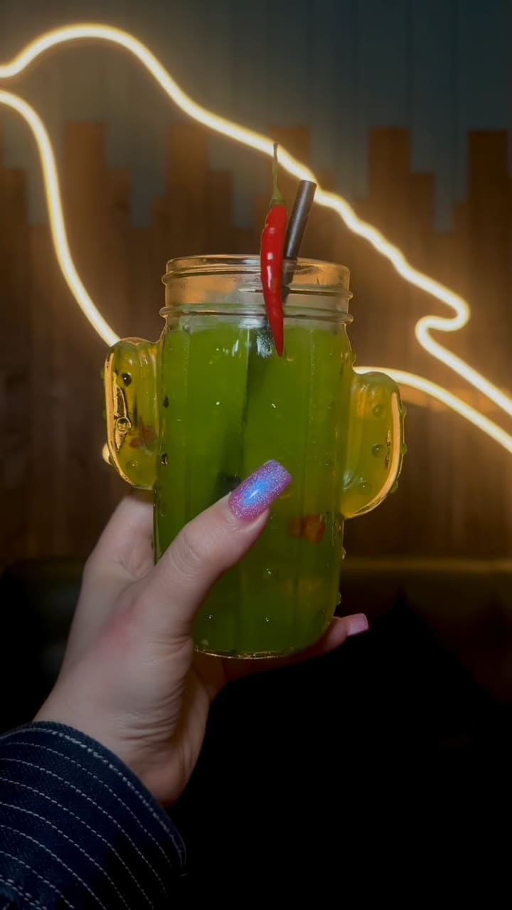 This TikTok video showcases Tequila Mockingbird, a chain of bars in London. It features various cocktails being prepared by bartenders, interspersed with shots of friends enjoying drinks and the bar's atmosphere.  The video highlights a January cocktail sale, with 2-4-1 deals and promotional pricing on wine, prosecco, beer, and shots.  The drinks include a green cocktail served in a cactus-shaped glass and a pink cocktail served in a tiki mug.  The overall tone is upbeat and celebratory. 
