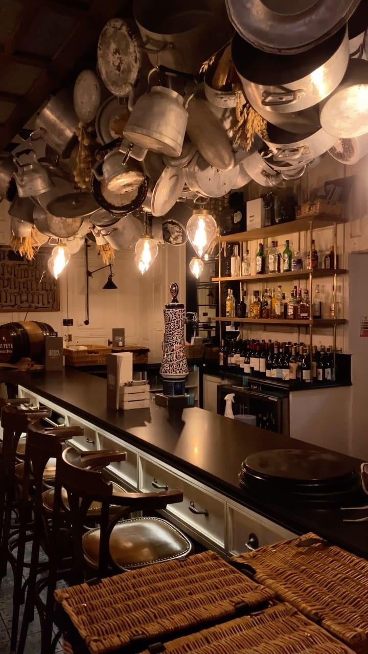 The video showcases a meal at Iberica restaurant in London, featuring a variety of tapas and other Spanish dishes.  The setting is a dimly lit, upscale restaurant with a stylish interior. Dishes shown include an artisan cheese and Iberian ham selection, pan con tomate, patatas bravas, serrano ham croquettes, pear and spinach salad, secreto Iberico pork with potatoes, black squid ink rice with prawns, and churros con chocolate.  The presentation is generally sophisticated, with dishes artfully arranged on plates.  No specific dietary information is provided, beyond the churros being marked as vegetarian. The main focus is showcasing the food and ambiance of the restaurant.