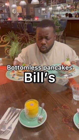The video showcases Bill's restaurant, focusing on their bottomless pancakes deal for £9.50.  It features two pancake options: one with chocolate sauce, chocolate biscuit crumbs, strawberries, and ice cream; the other with fruit (strawberries, bananas, and blueberries) and pancake syrup.  Both options are served with unlimited hot drinks (cappuccino, matcha, latte shown). The restaurant's interior is also shown. The main focus is a meal showcase.
