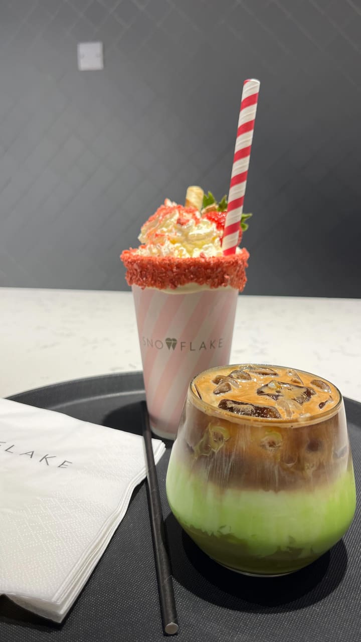 The video showcases Snowflake, a gelato and coffee shop located at the 02 in Greenwich, London.  It features various desserts, including gelato in cones and cups with different flavor combinations, a strawberry sundae milkshake, and an iced pistachio latte. The presentation emphasizes the vibrant colors and creamy textures of the gelato and the appealing visual presentation of the drinks and desserts.  No specific dietary information is provided.