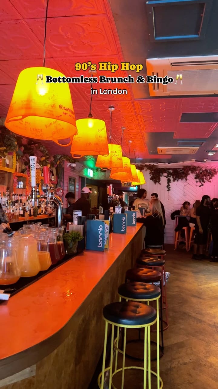 The video showcases a 90's hip hop bottomless brunch and bingo event at Barrio Bars in Shoreditch, London.  It features various shots of the venue's vibrant atmosphere, including the bar area, indoor and outdoor seating, and the crowd enjoying the event. Food shown includes sharing boards with tortilla chips, dips, and quesadillas.  Drinks include cocktails and bubbly. The main focus is on the lively atmosphere and the event itself, highlighting the fun, energetic crowd and the music.