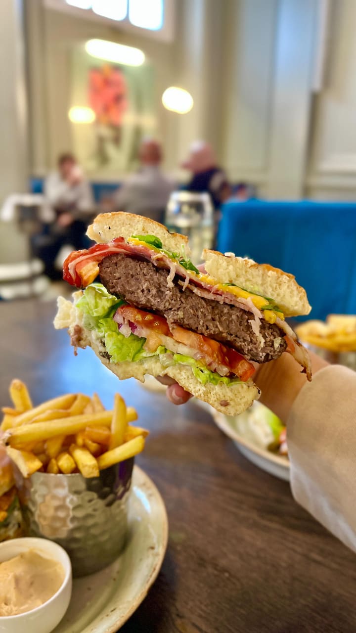 This video promotes a bottomless brunch at 'The Soak' restaurant in London. It showcases the stylish interior, the bar, and various dishes including a beef burger, a chicken burger, both served with fries, eggs benedict, and salt and pepper squid. The video also features glasses of sparkling wine being poured and enjoyed. The voiceover highlights the value (£43 for two courses and bottomless drinks), the quality of the food, and the attentive service.