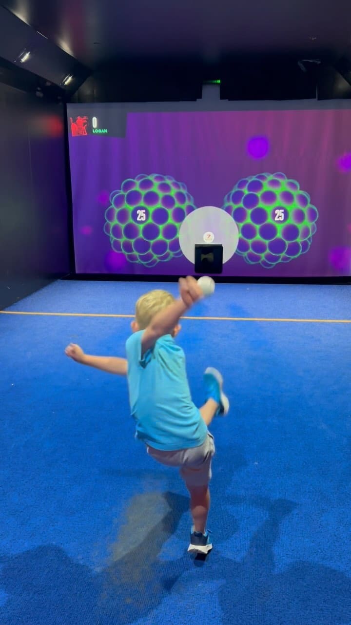 The video showcases a family's experience at TOCA Social, an entertainment venue at The O2 arena in London. It features various interactive football games projected onto a screen, with the family members actively participating.  No specific food items are shown, though drinks are visible, and the caption mentions food is available at the venue. The focus is on the fun and engaging activities available, rather than a detailed food and drink presentation.