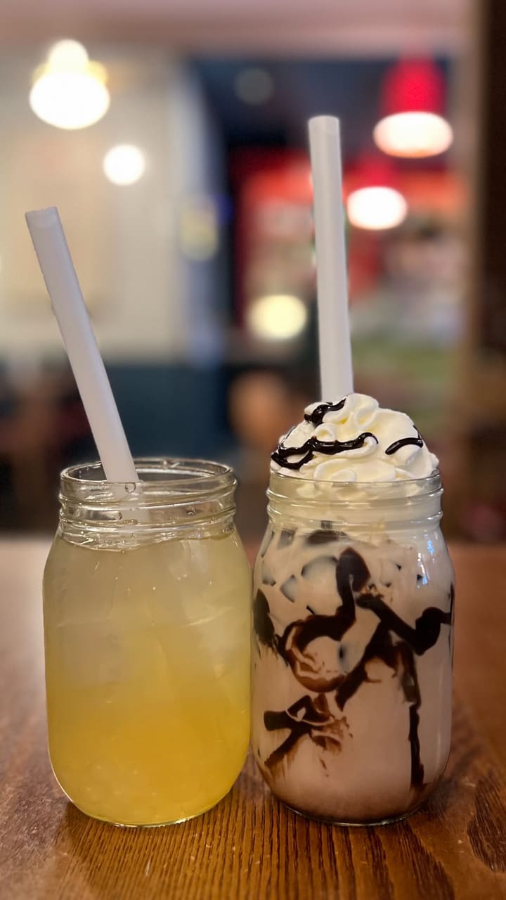 The video features two influencers visiting Rosa's Thai restaurant to celebrate Songkran. They showcase the restaurant's exterior and interior, highlighting the decor and atmosphere. They order and try limited-edition bubble teas (jasmine and chocolate options) and a food dish (noodles) from the lunch menu. The video includes close-ups of the menus, drinks, and food. The influencers express positive reactions to the drinks. The video mentions Songkran festivities and the restaurant's lunch menu offer.