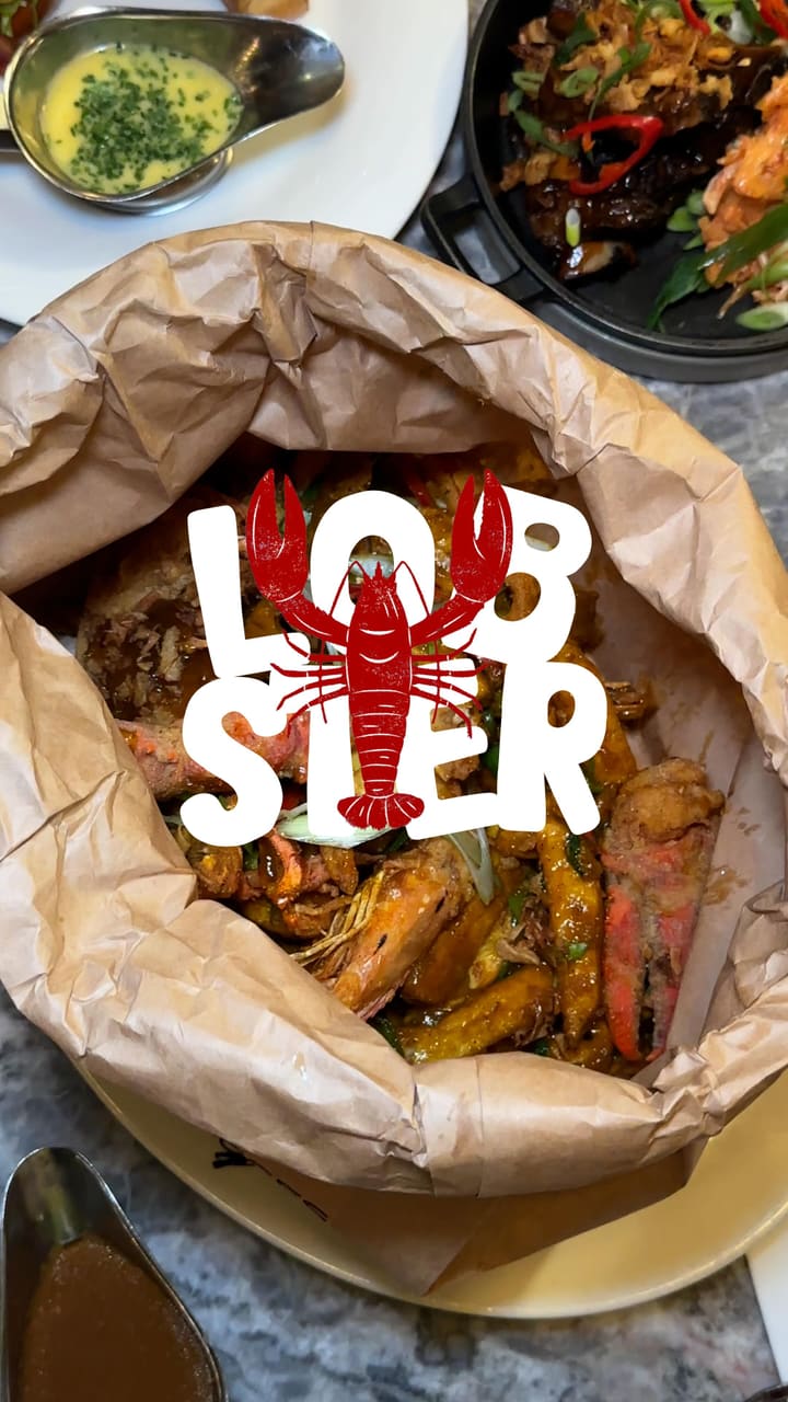 A food influencer reviews the new 'Lobster Spice Bag' at Burger & Lobster, showcasing the preparation process in the kitchen and their personal taste test of the dish. The video highlights the unique fusion of Irish-Chinese flavors and the generous portion size, while also giving a glimpse of the restaurant's atmosphere and other menu items.